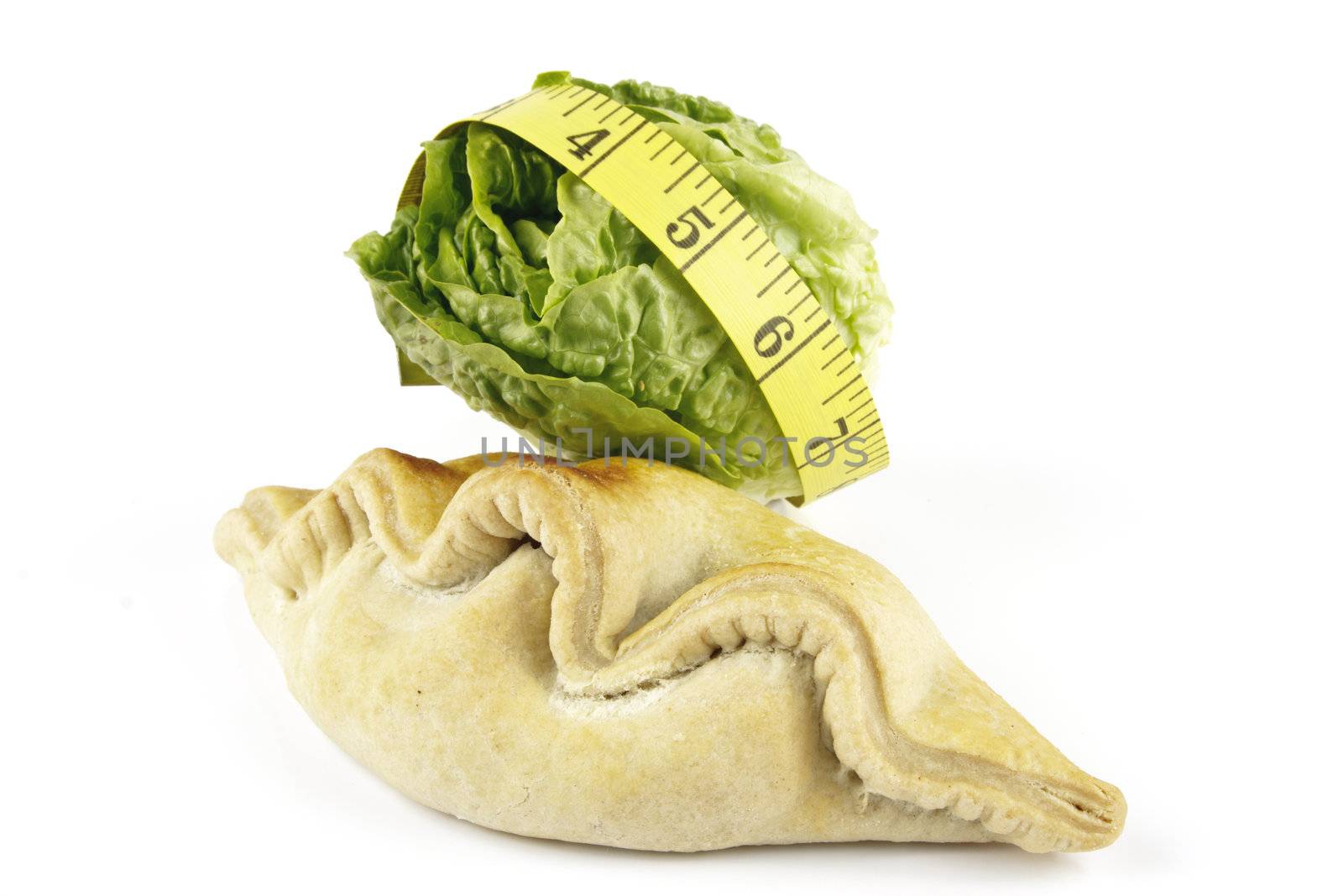 Contradiction between healthy food and junk food using a green salad lettace and pasty with a yellow tape measure on a reflective white background 