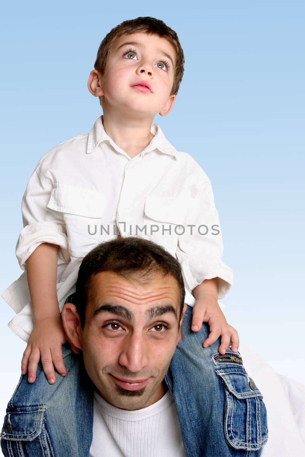 Sky is the limit....   A child sits atop his father's shoulders looking skyward.