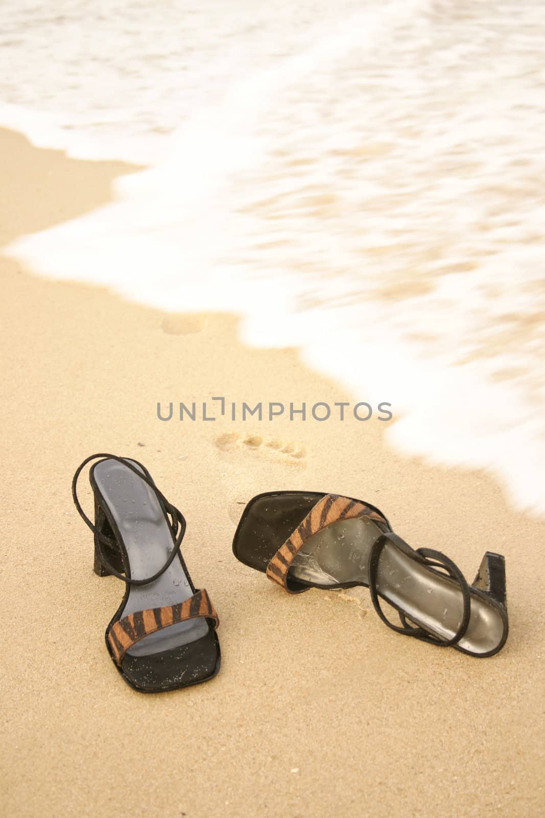 Sandals sitting on the sand as water laps close by.  Maroubra Beach East Sydney dusk light 