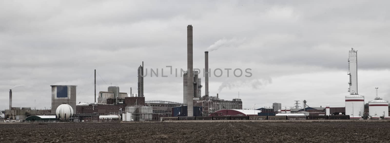 Industrial buildings behind a field  by gemenacom