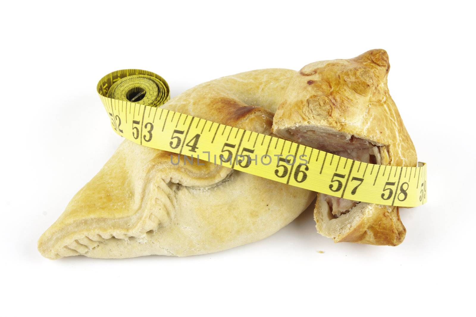Single golden pasty with pork pie and yellow tape measure on a reflective white background