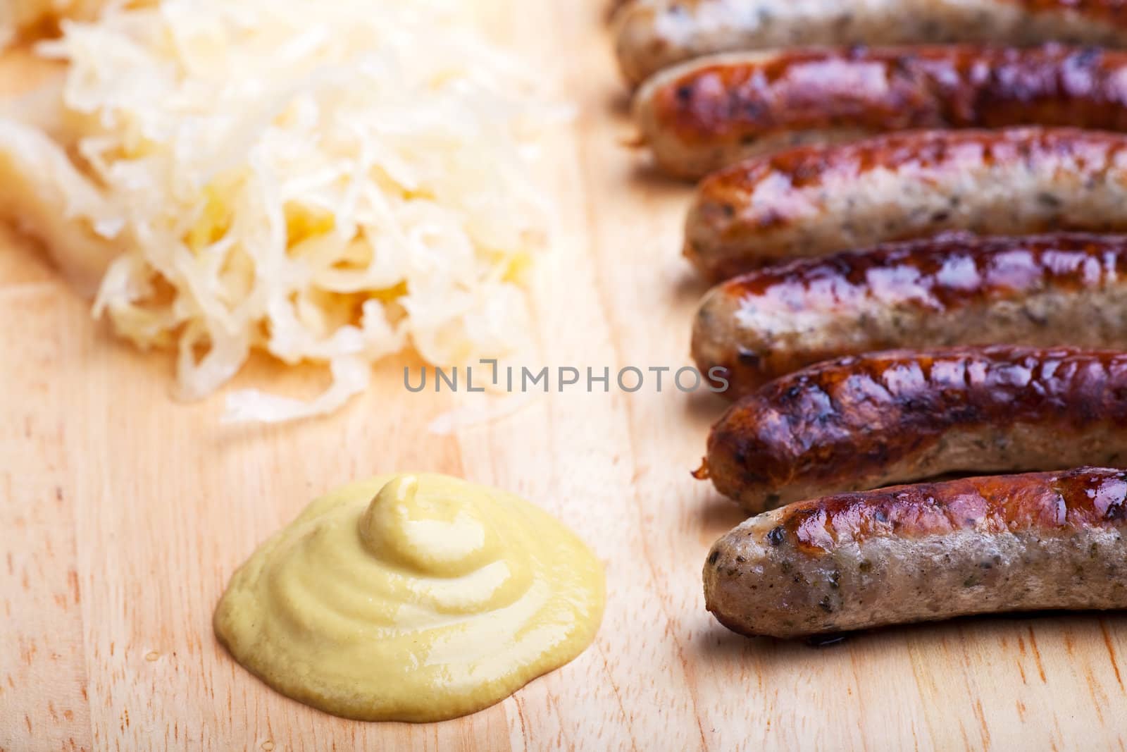 fried sausages,mustard and sauerkraut on a wooden plate by bernjuer