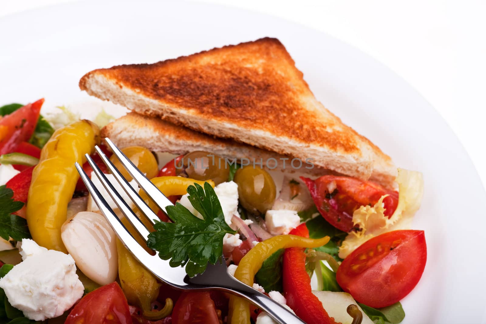 greek salad on a plate with a slice of toast bread