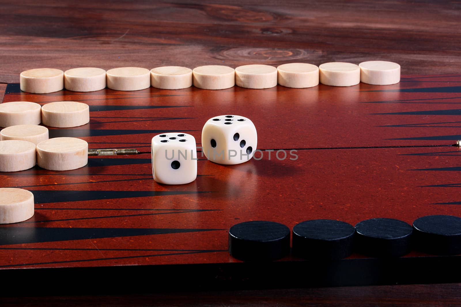 Backgammon, in the foreground in focus black counters, on a background of a counter of the contender and cubes.