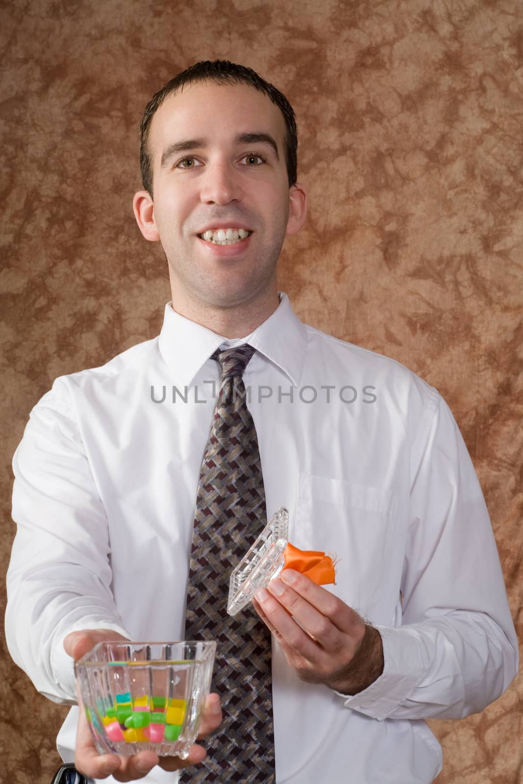 A young businessman offering some candy from a glass dish