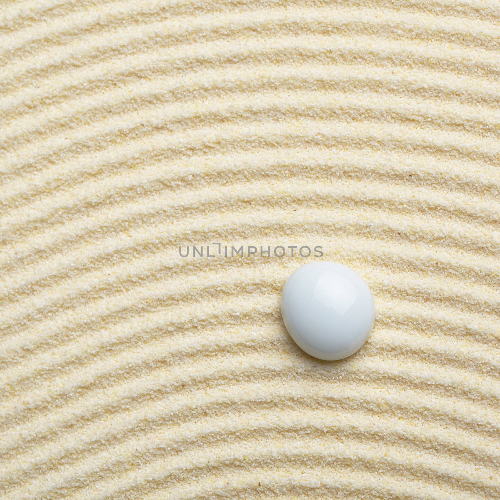 Round ceramic stone on a surface of yellow sand - square composition