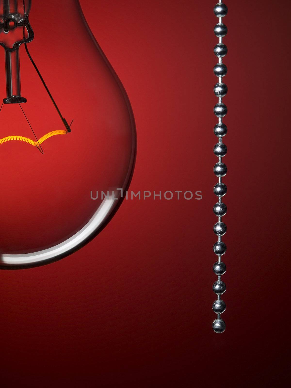 Close up on a transparent light bulb with a pull switch over a red background.