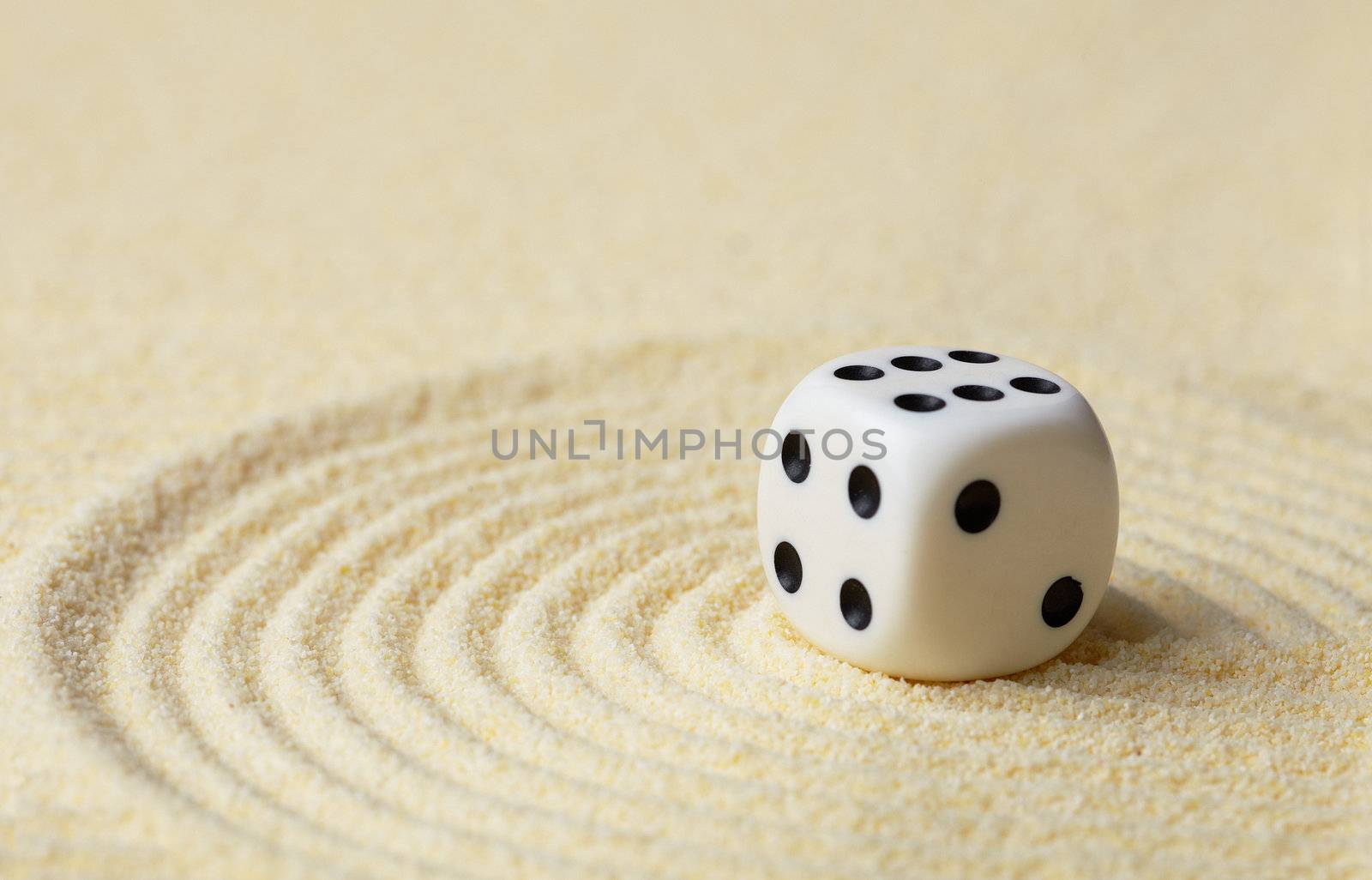 Dice with black dots against yellow sand