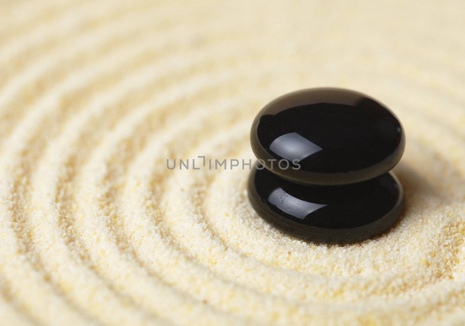 Two black stones put in a pile against sand
