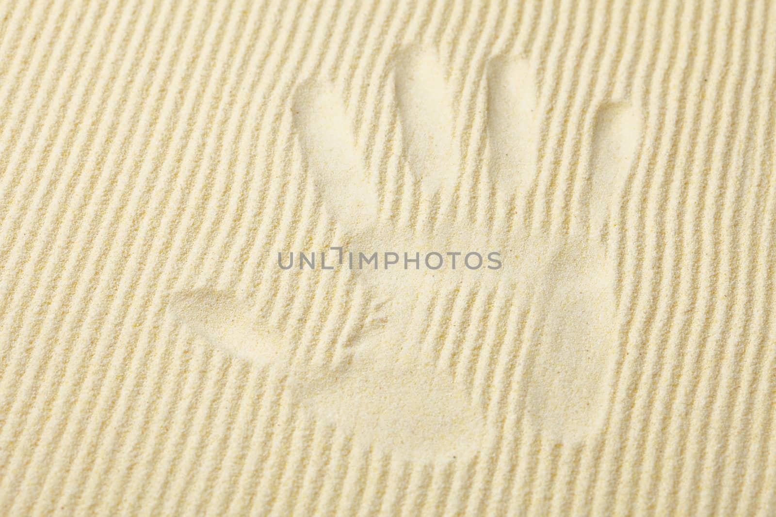 Trace from a palm on a surface of yellow sand
