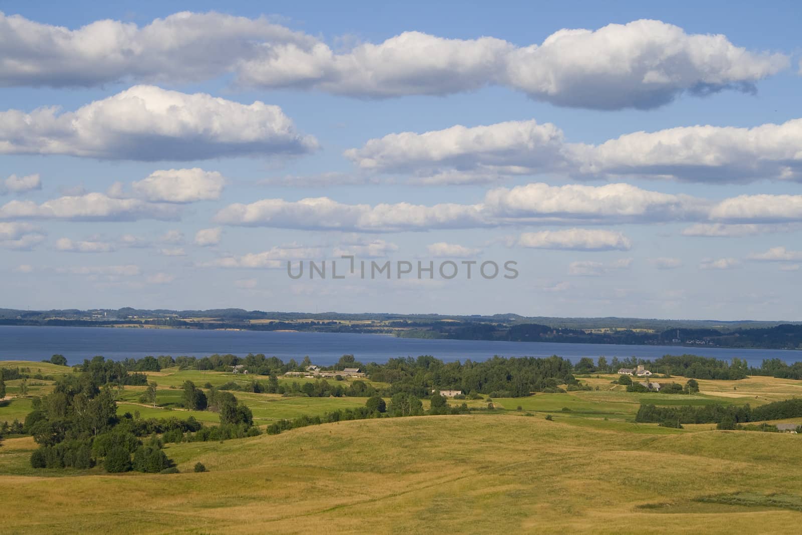 Landscape of fields and lake with clouds, captured in Latvia