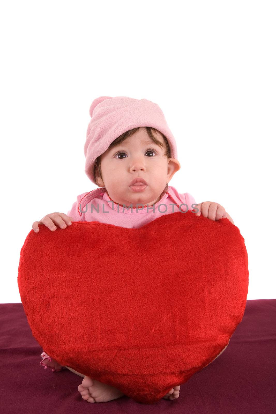 Cute little baby sitting with a big red pluche heart
