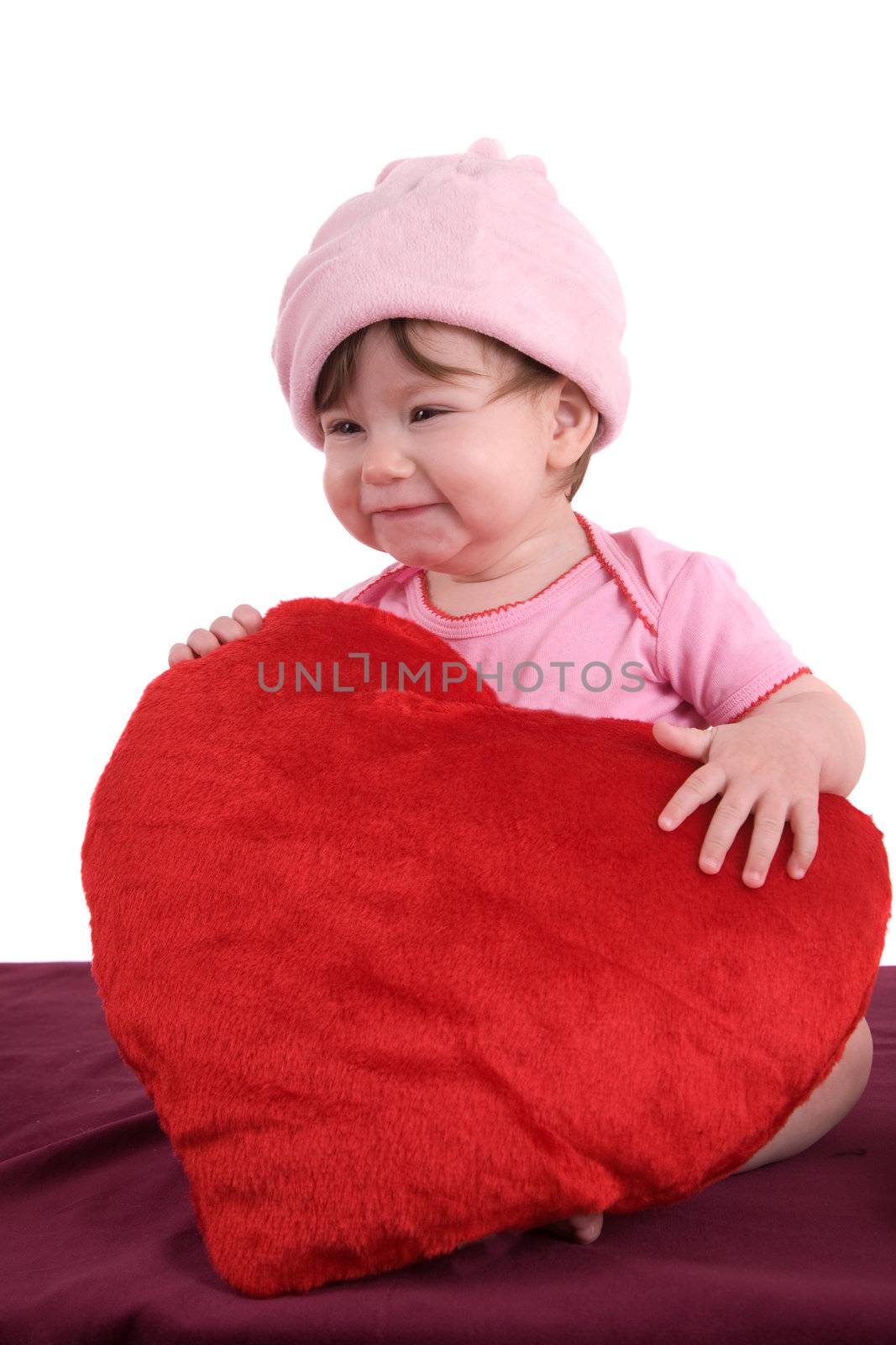 Cute little baby having fun and laughing while holding a big red heart