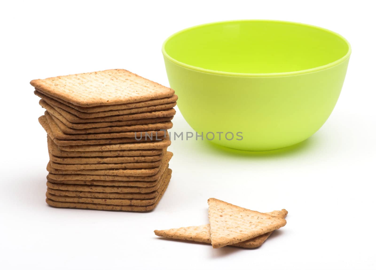 A stack of crackers  and green cup over white