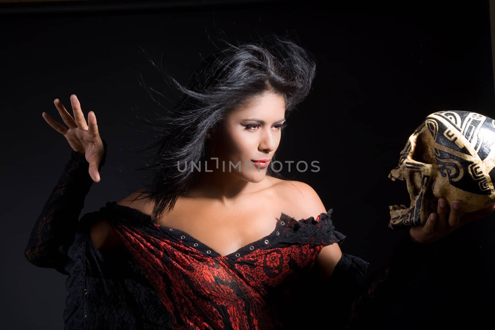 Beautiful latino witch casting a spell using a skull