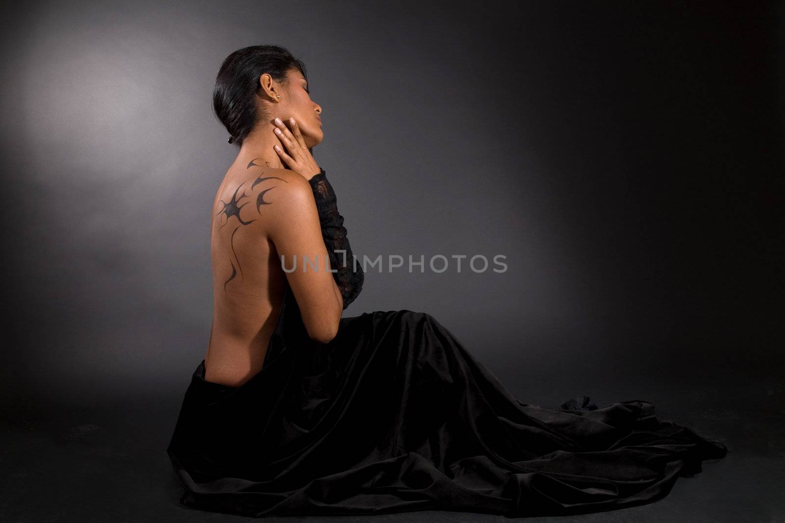 Beautiful woman sitting on black background surrounded by black velvet