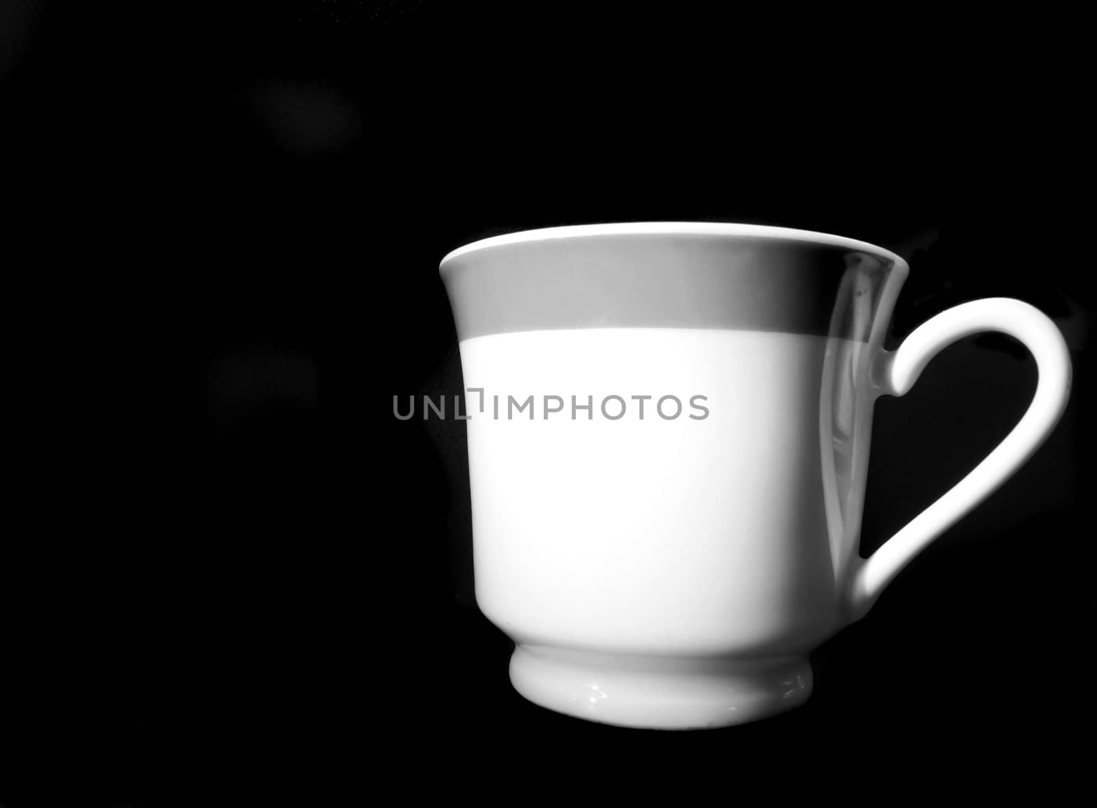Fine china cup in monochrome, on black background