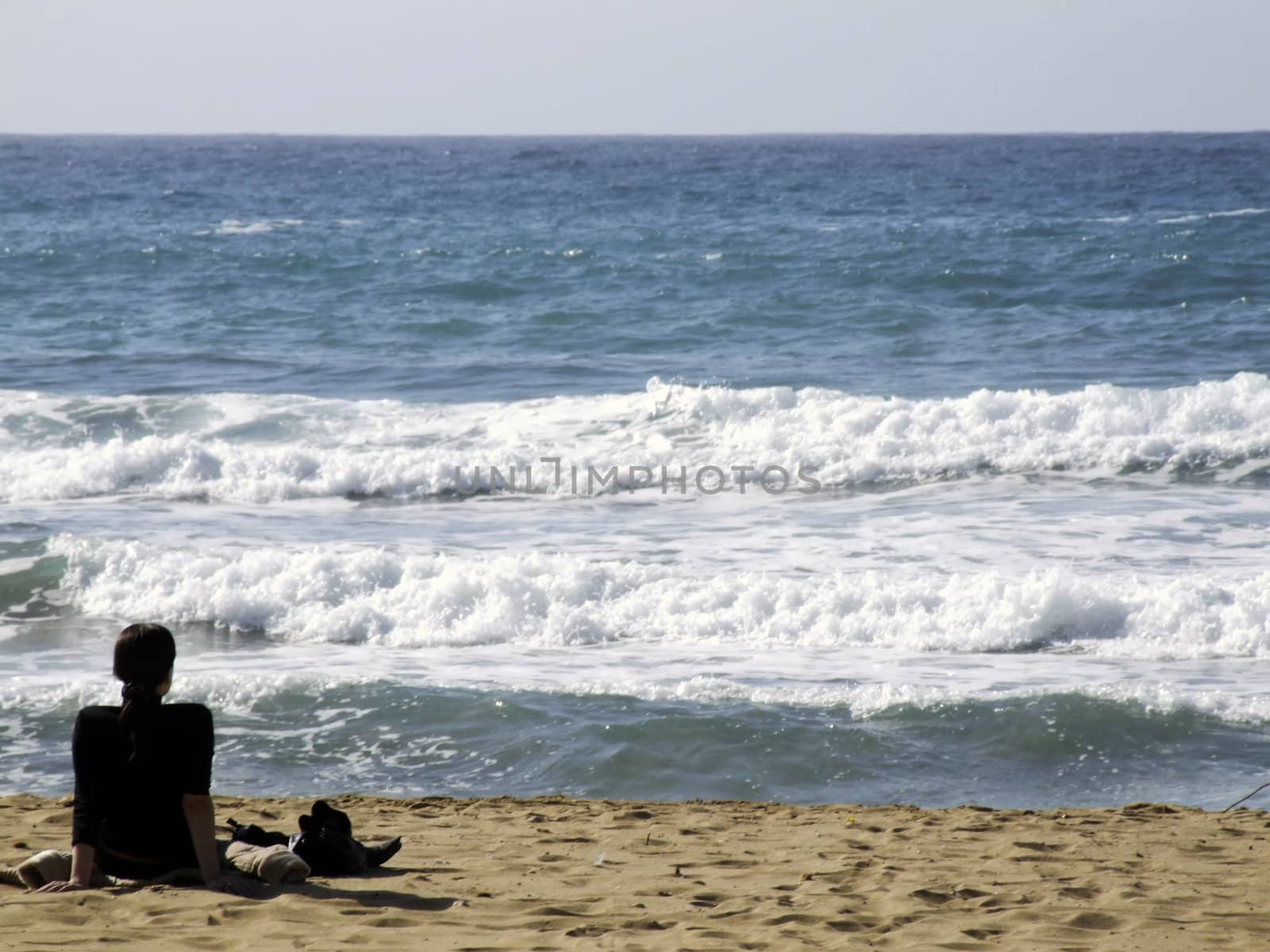 Young relaxed woman watching glistening waves of the ocean
