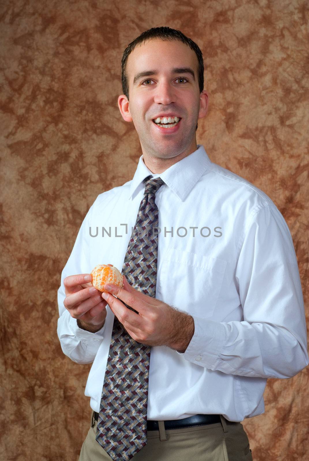 A businessman wearing a tie is going to eat a peeled orange for a snack