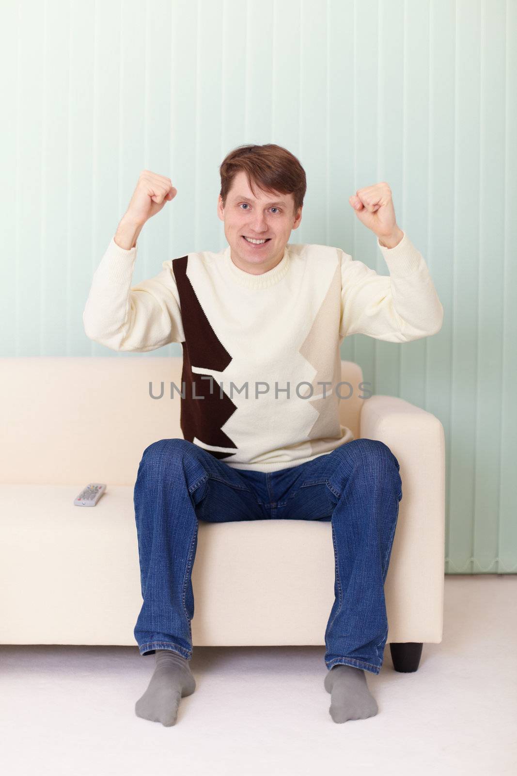The person on a sofa watches football on TV
