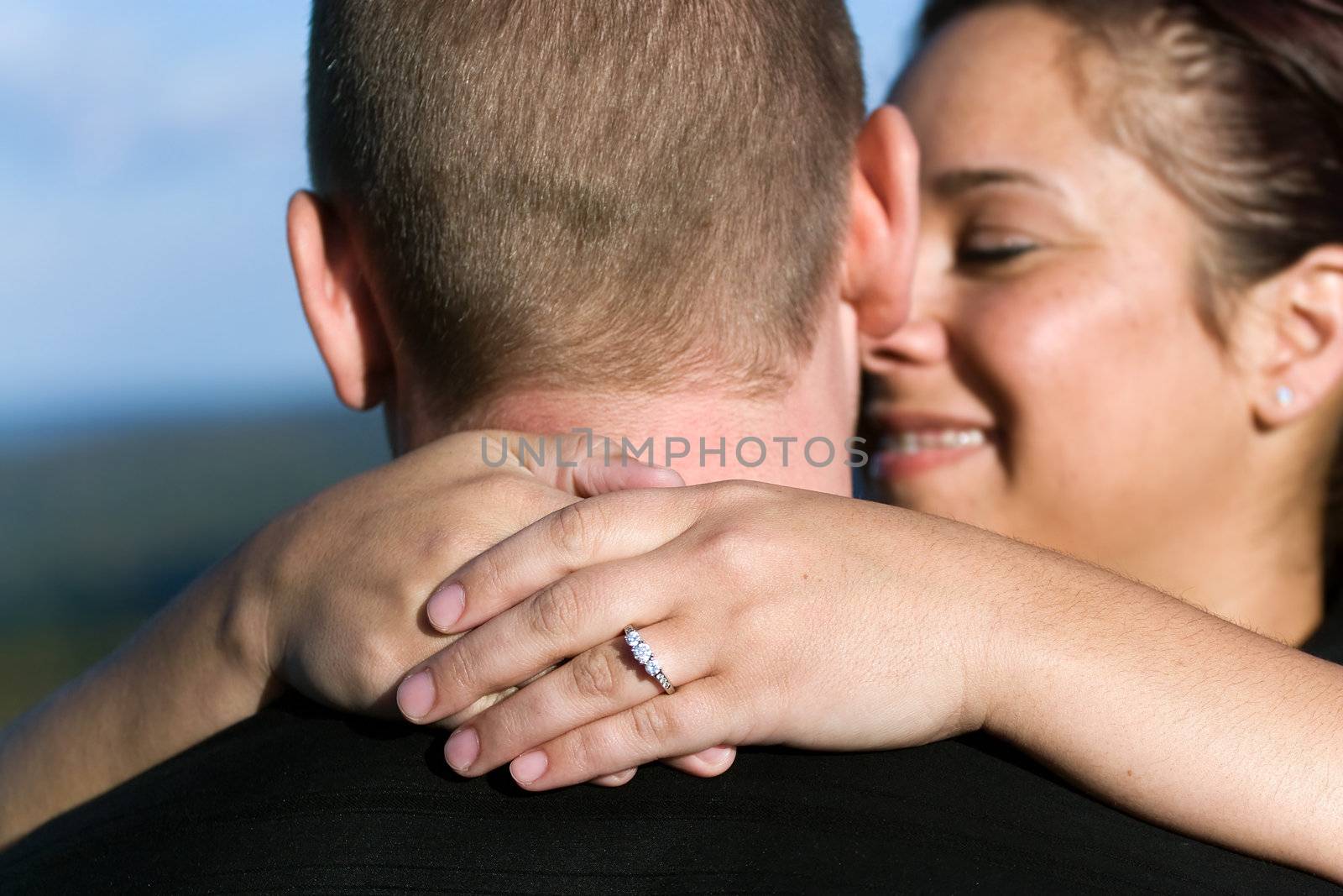 A young happy couple that just got engaged.  Shallow depth of field with focus on the diamond engagement ring.