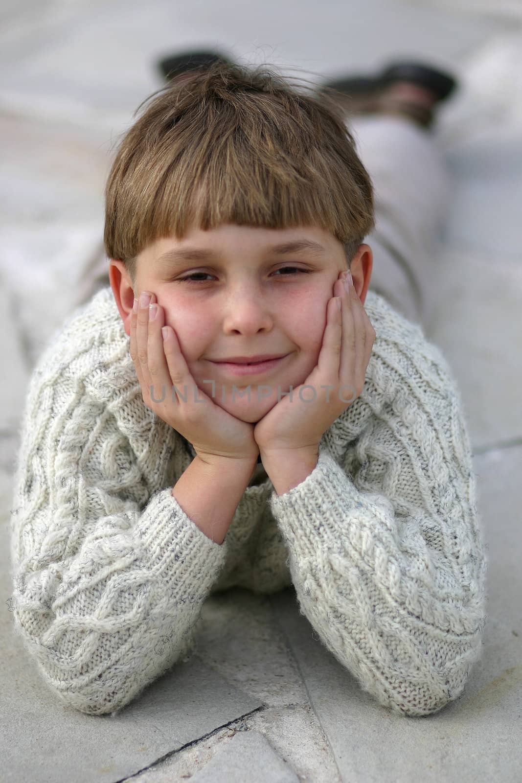 A boy lying casually on a pretty stoney pathway.