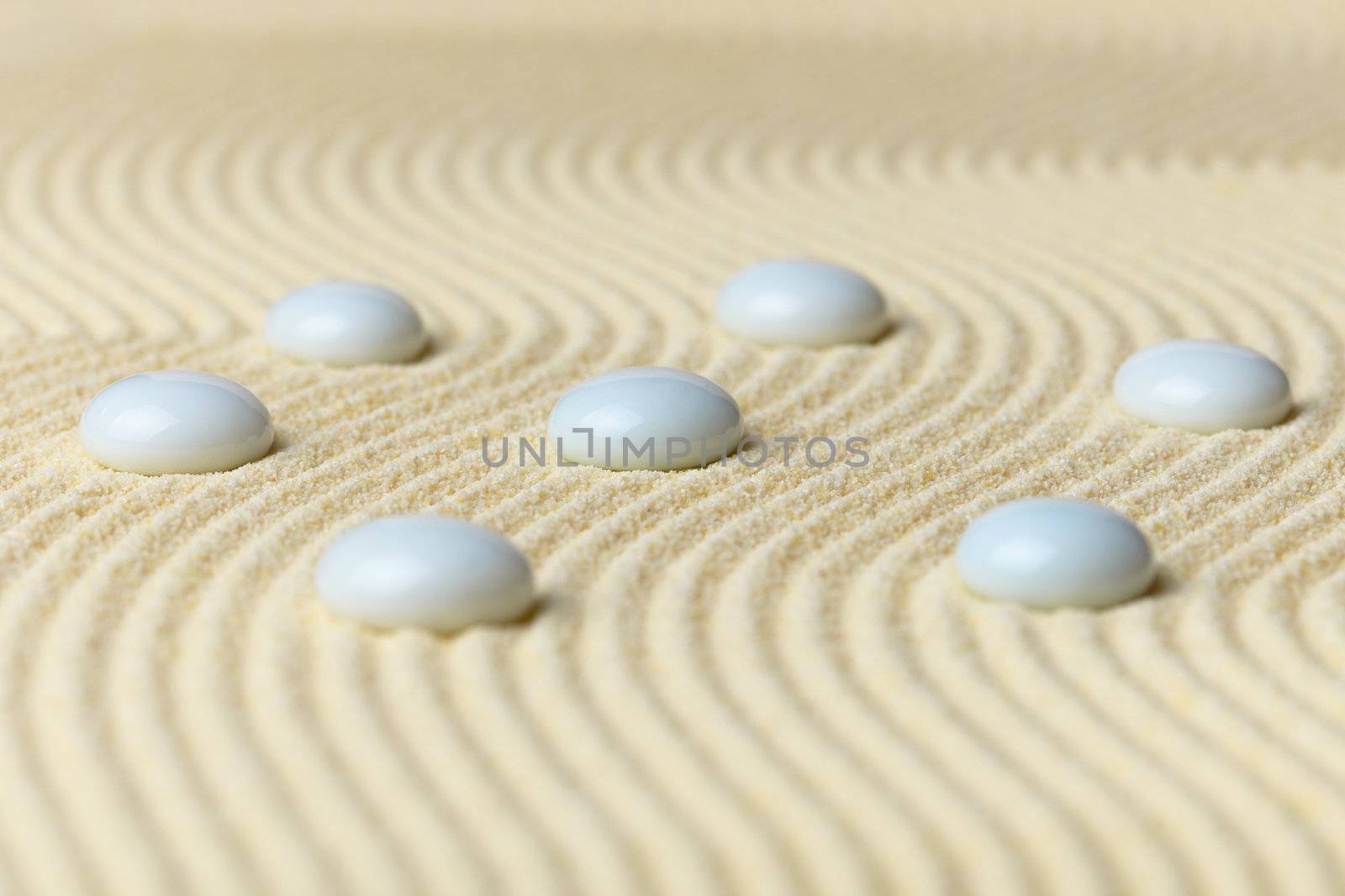 White drops on a surface of yellow sand - an abstract composition