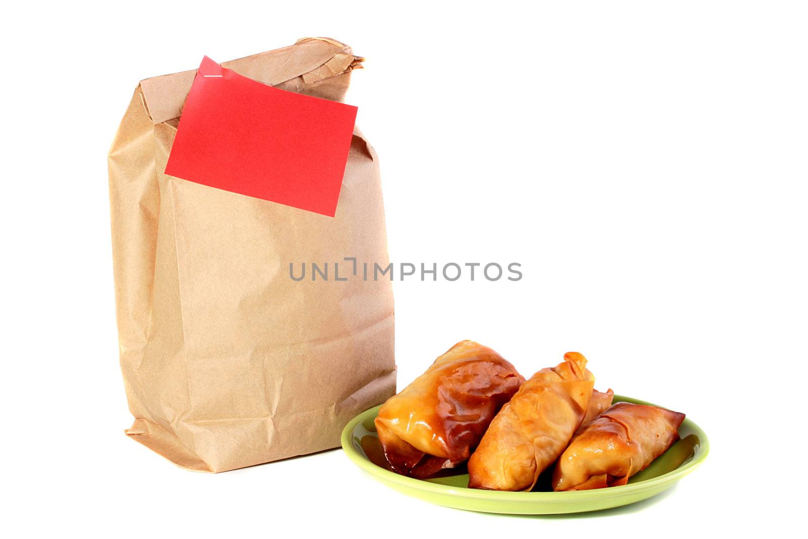 Paper package for a dinner at office or at school and pancakes with a stuffing on a plate.