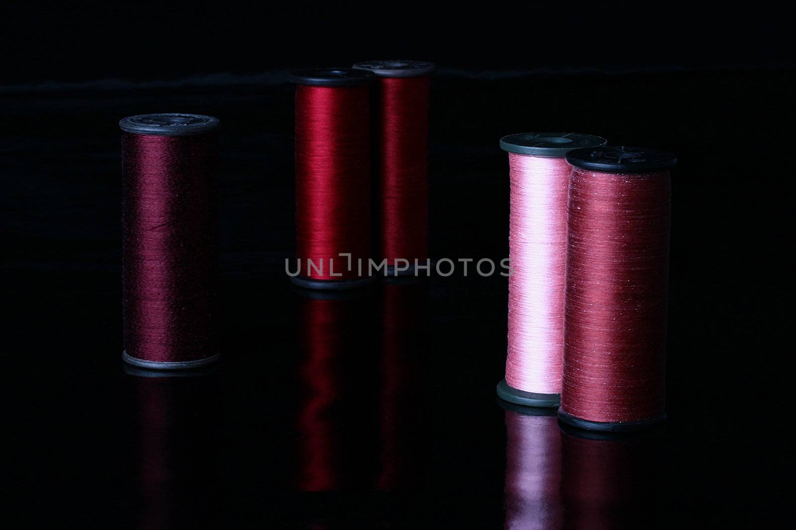 Colour threads on coils, a background - black, reflecting.