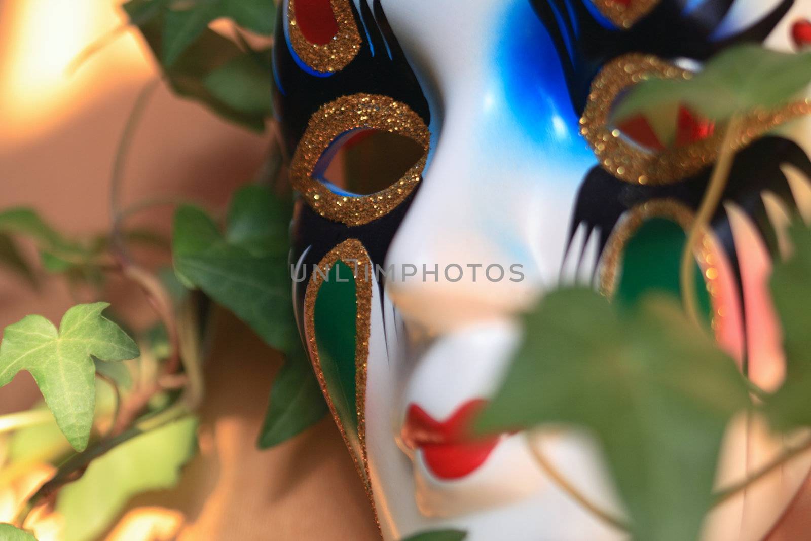 Closeup of nice ceramic venetian mask on background with green leaves