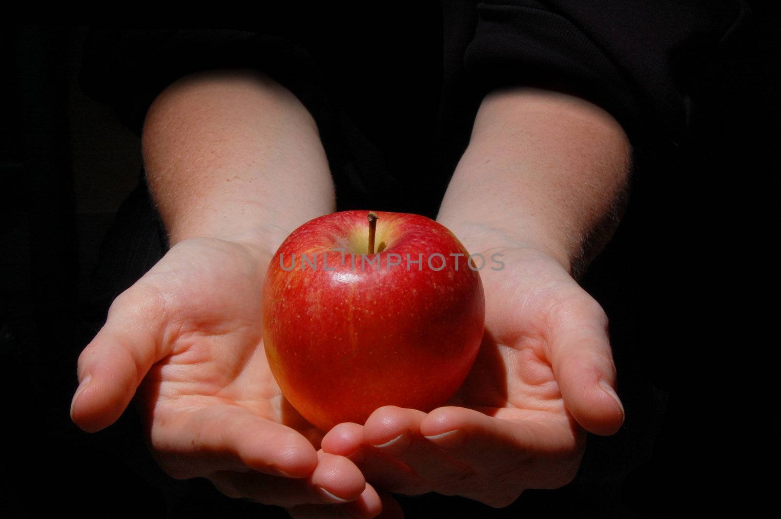 hand with red apple fruit on black background