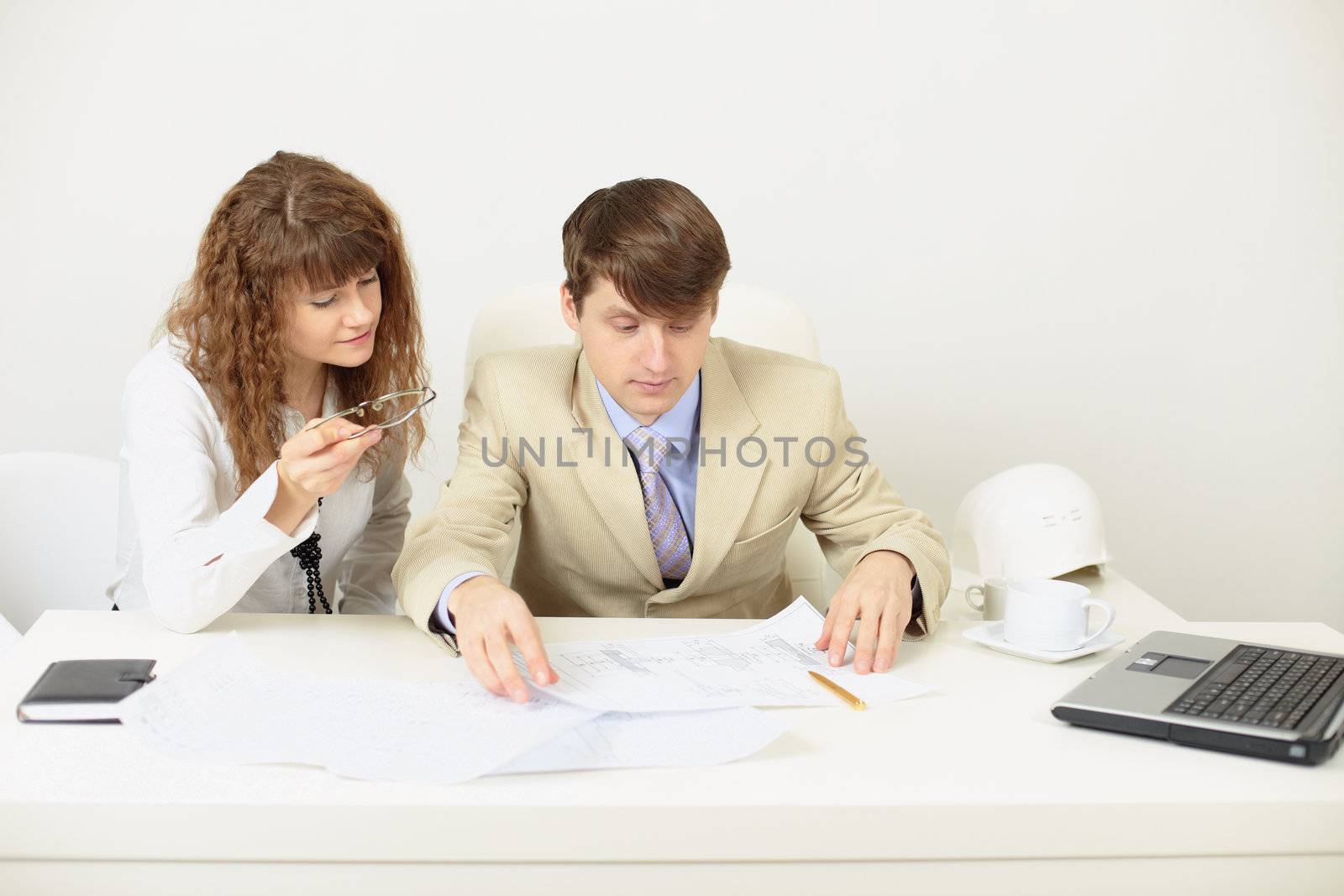 Young engineers plan work sitting at a table by pzaxe