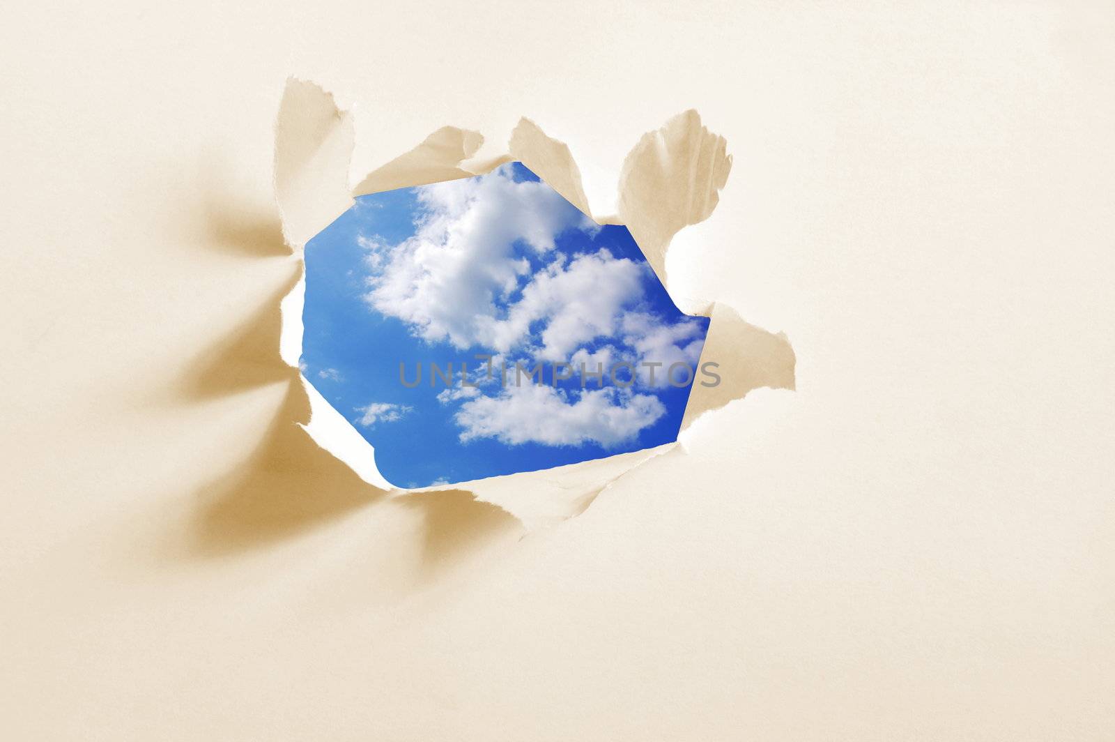 cloudy sky behind paper hole showing freedom