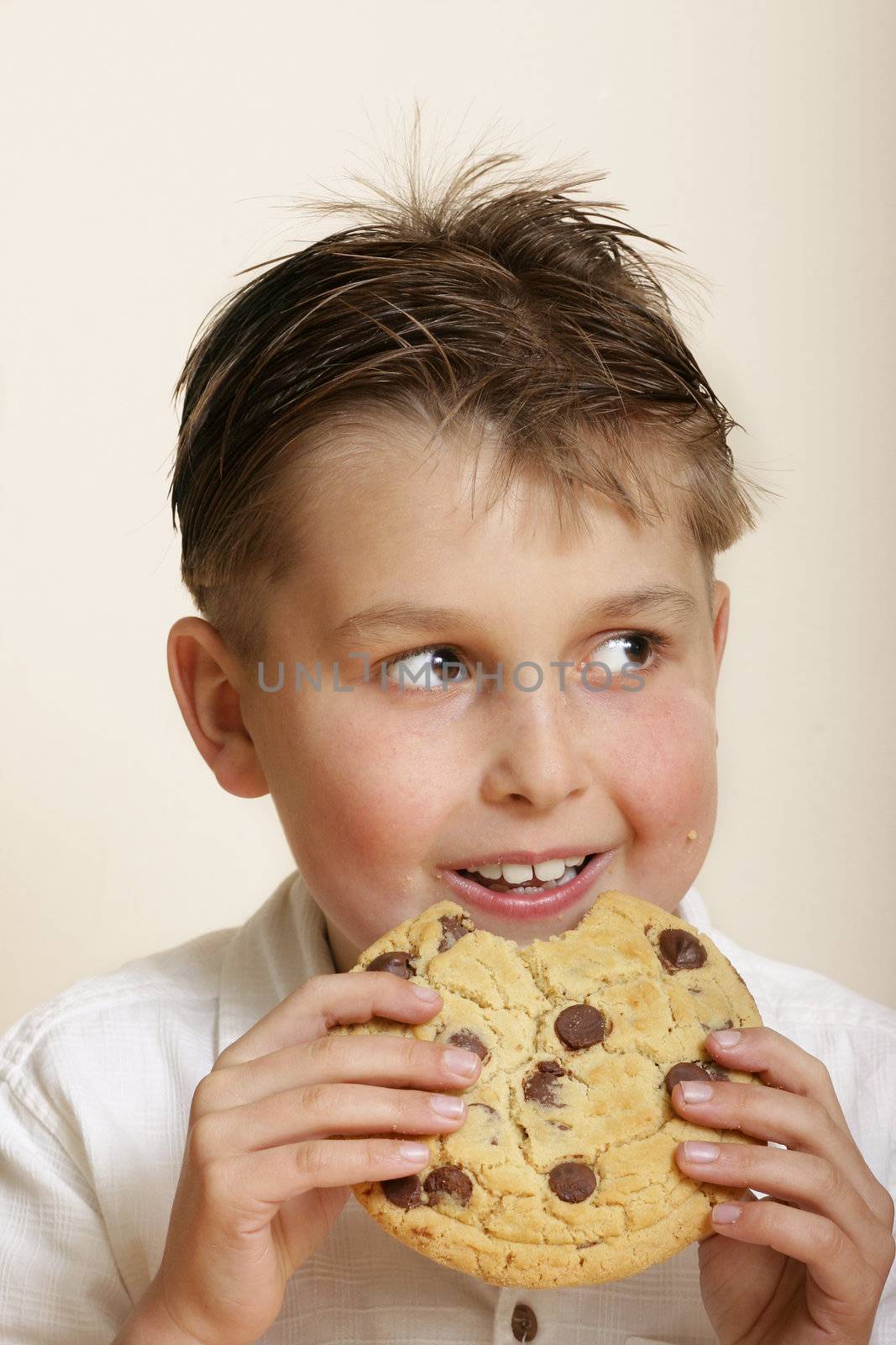 Boy with a very large choc chip cookie.  