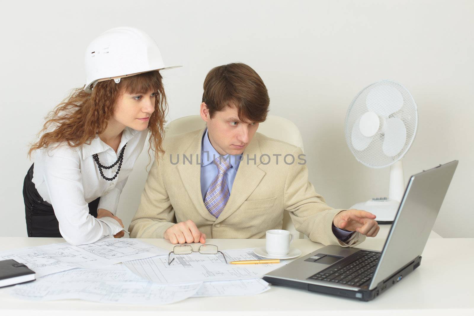 Two young experts are occupied by work at office