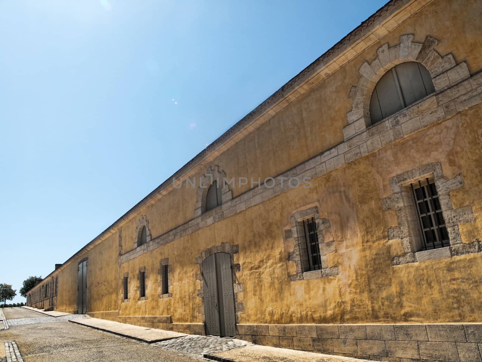 Big yellow house with an empty  alley in France under pure blue sky