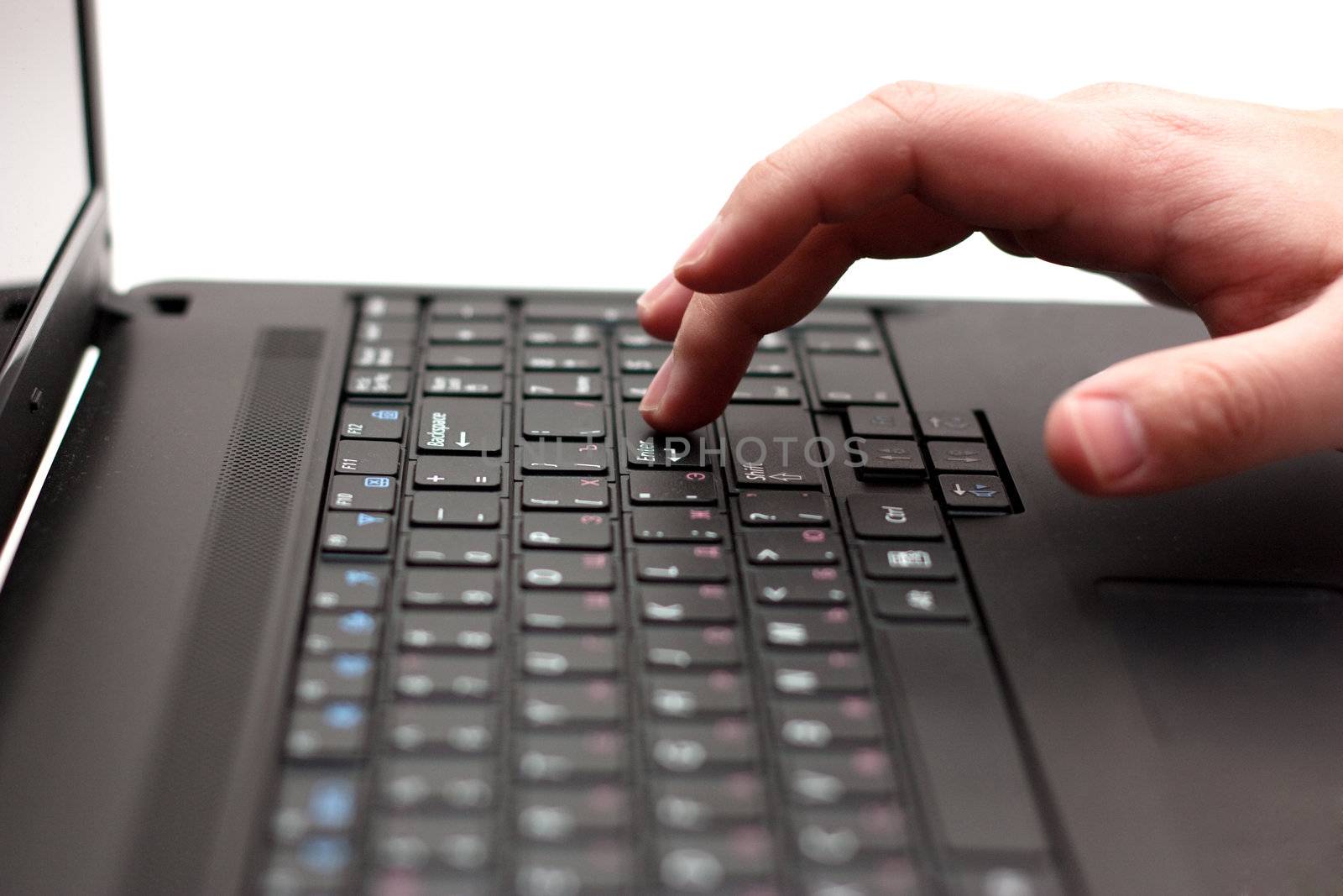 Close-up of finger over black laptop keys going to press enter button