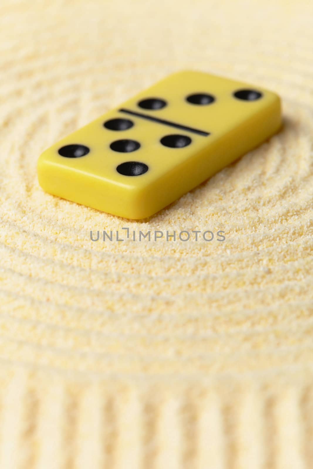 Domino on a surface of yellow sand - an art miniature