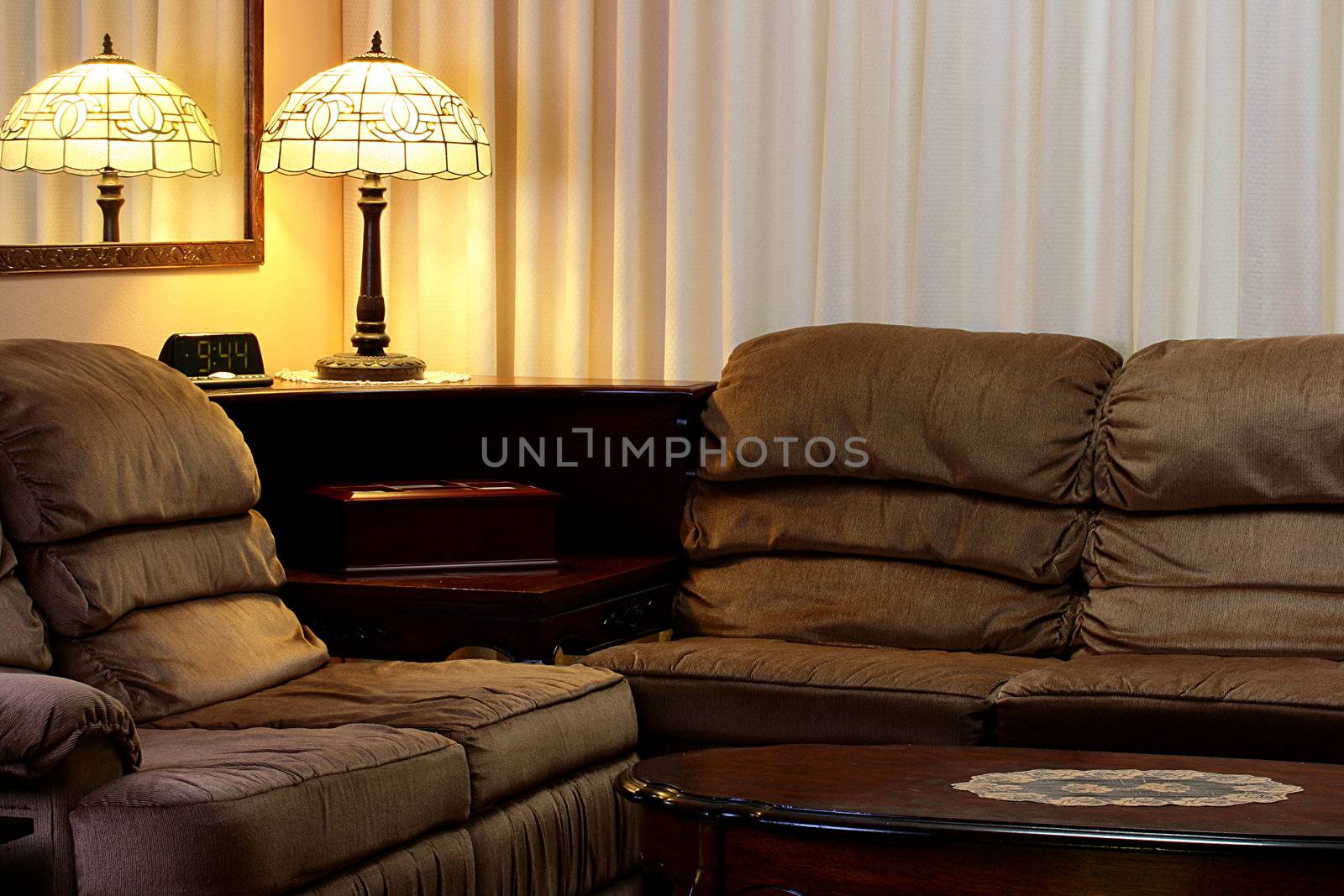 Interior of a room with an angular sofa and a desk lamp.