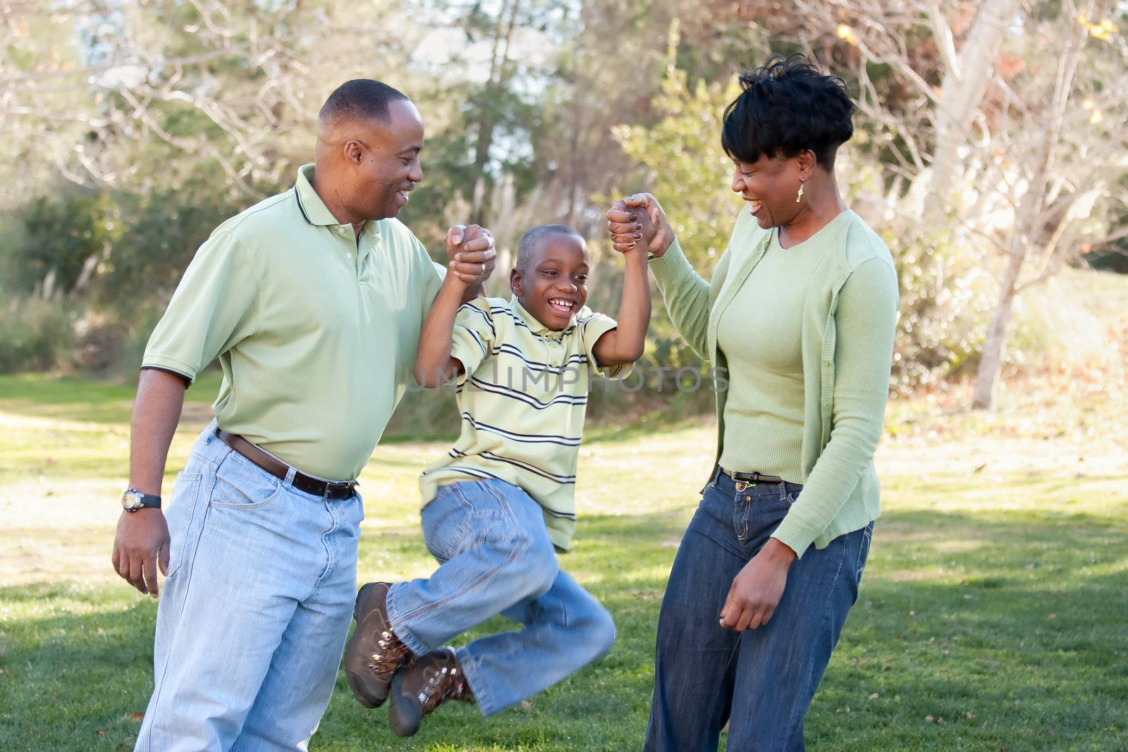 Playful African American Man, Woman and Child Having Fun in the Park.