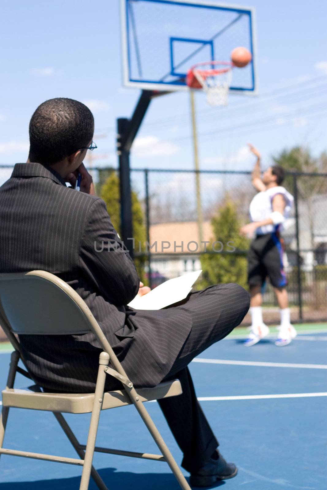 A basketball coach or scout recruiter observes an athlete while he warms up.