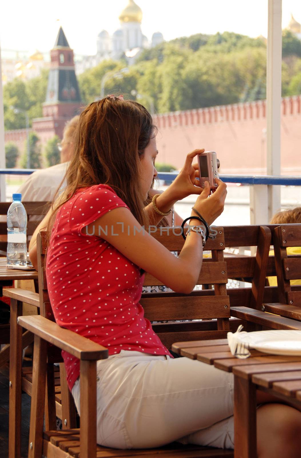 teenage caucasian girl tourist with camera on passenger boat during cruise through Moscow