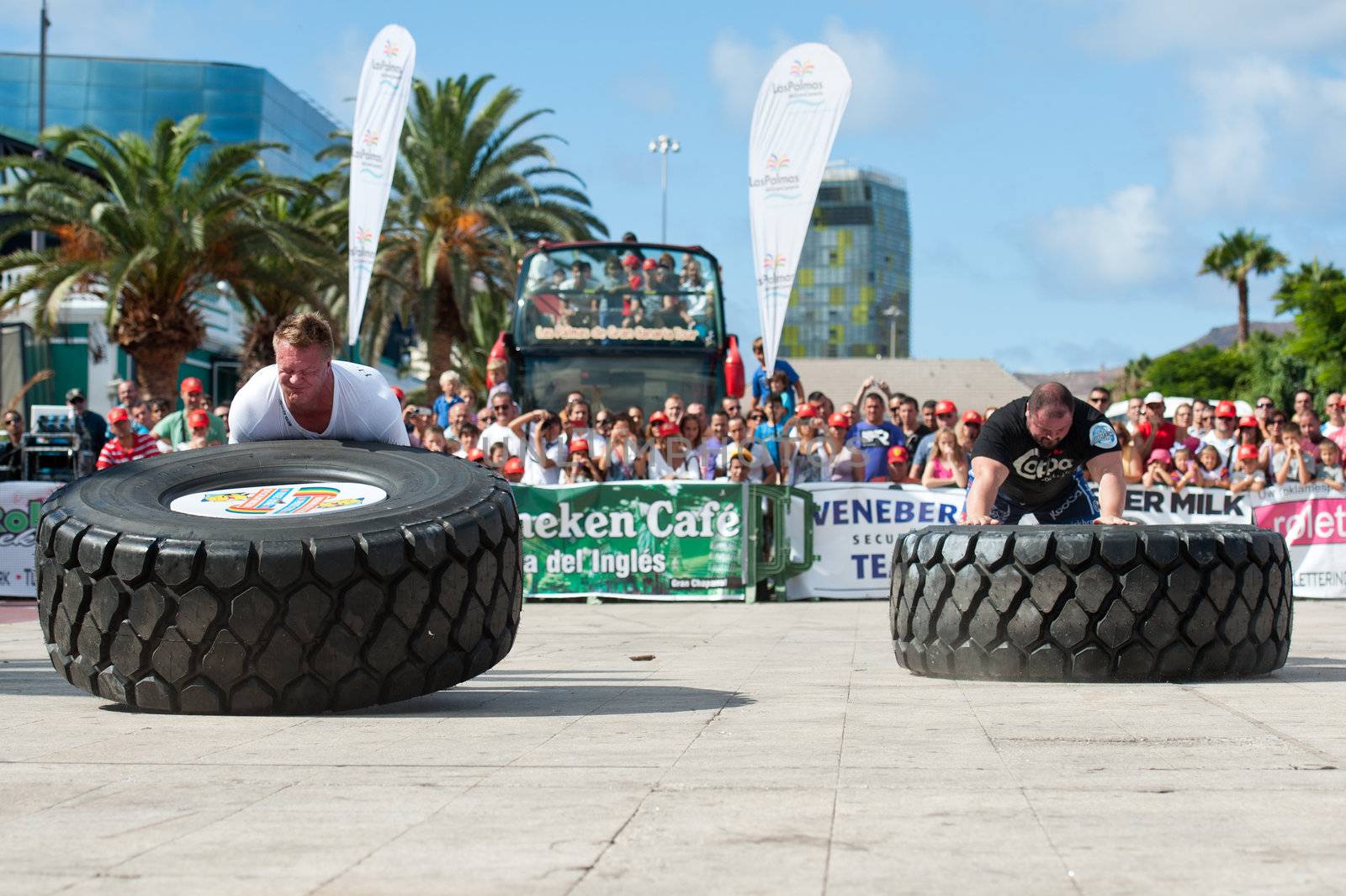 CANARY ISLANDS - SEPTEMBER 3: Tomi Lotta (l) from Finland and Warrick Brant from Australia (r) lifting a wheel during Strongman Champions League in Las Palmas September 03, 2011 in Canary Islands, Spain