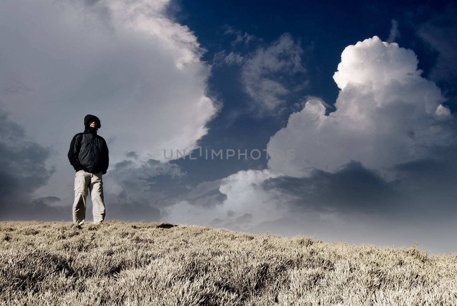 Lonely man stand and watch on the hill with dramatic heaven.