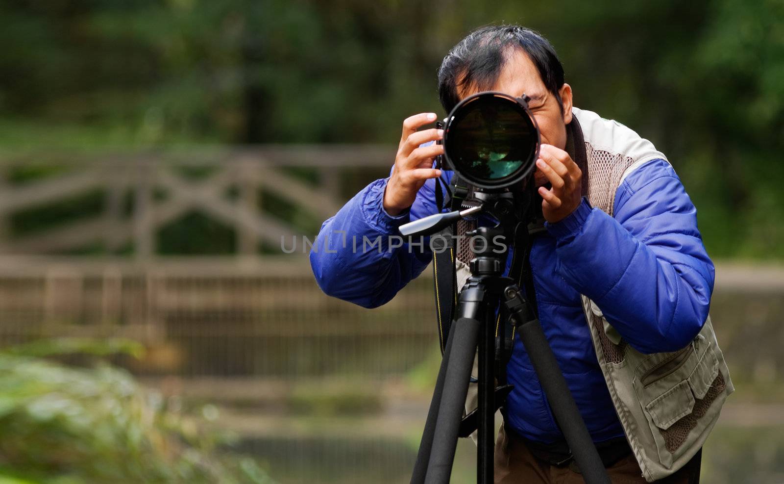 Asian photographer in outdoor with heavy cloth and black hair set camera already to take picture.