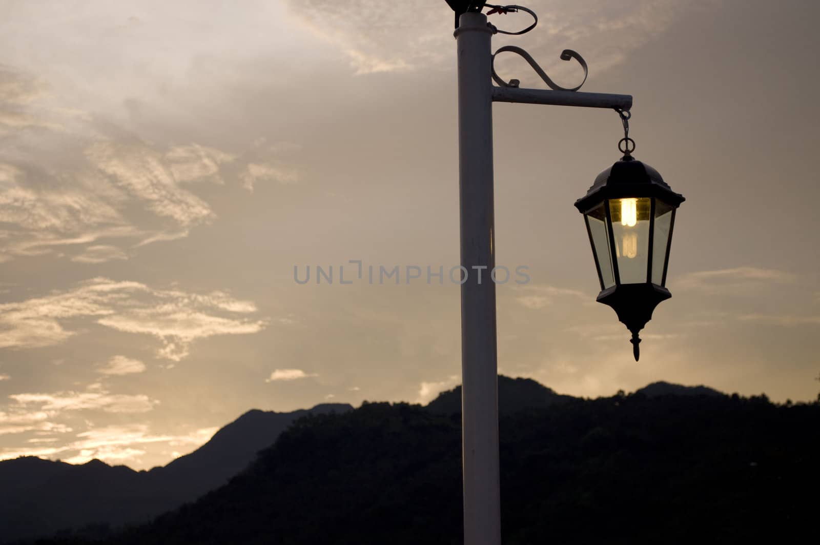 An outdoor lamp against a mountain background during sunset.