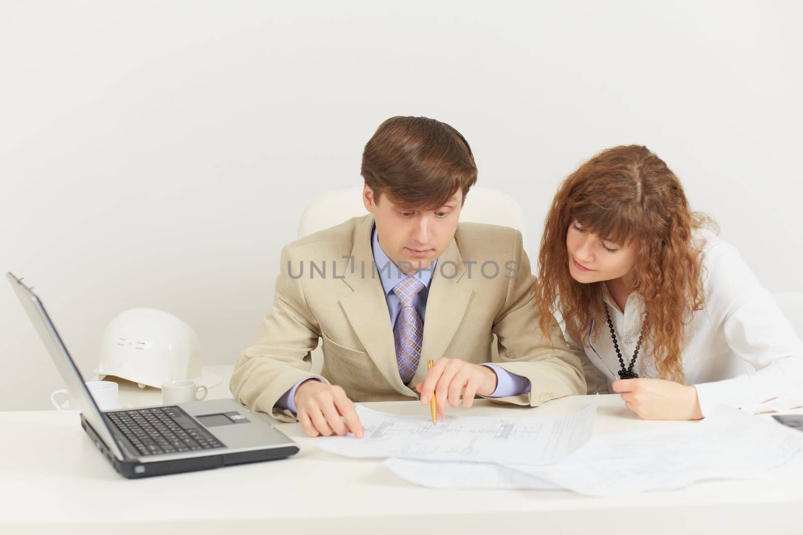 Two young businessmen work with documents at office