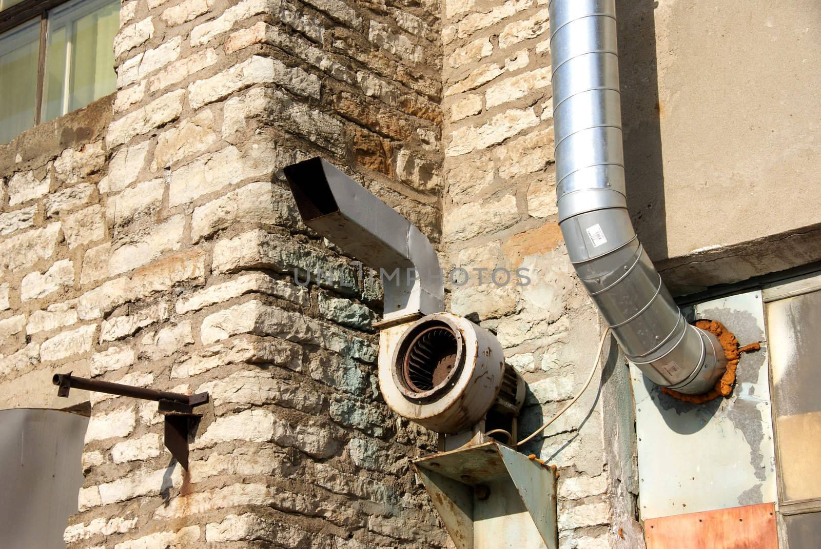 Pipes of ventilation are located on a wall of an old  building