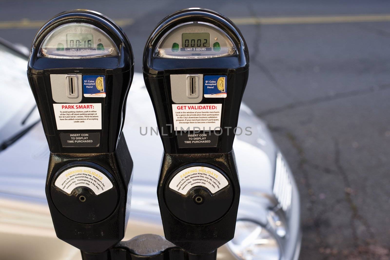 Closeup of Two Parking Meters in Front of a Parked  Car