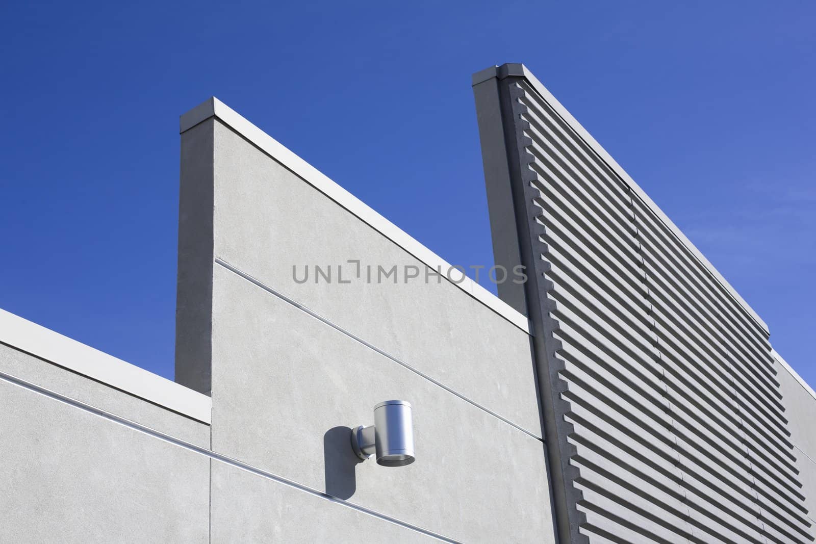 Modern Concrete Wall With Light Fixture in Front of a Bright Blue Sky